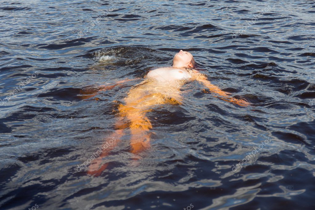 Nackte Frau schwimmt im Wasser auf dem Rücken.