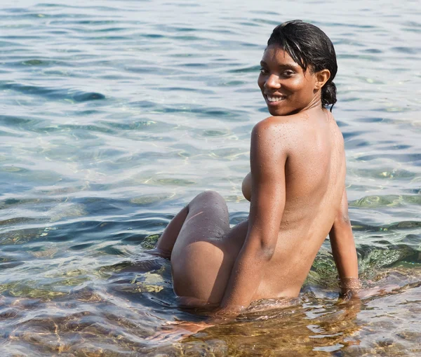 Black woman relaxing naked on the shore beach — Stockfoto