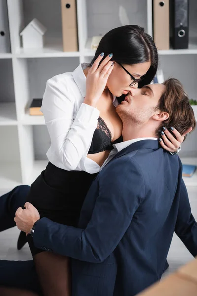 Sexy brunette businesswoman kissing young colleague on floor in office — Stock Photo