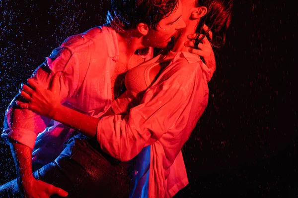 Vermelho e azul cores filtros imagem de mulher sedutora sexy molhada e homem apaixonadamente abraçando gotas de água no fundo preto — Fotografia de Stock